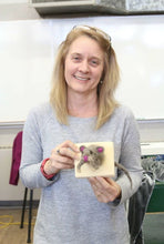 Load image into Gallery viewer, A light skinned blond teacher with blond hair and glasses on her head is smiling while holding up a fake felted taxidermry animal  on a plaque project ( a mouse that looks like its jumping through the plaque with its head out the front and  tail coming out the back)
