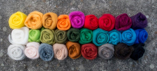 27 rolls of colorful wool roving rolled up in balls. Photo is taken from above looking downward